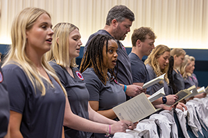 row of nursing students standing while reading from a program